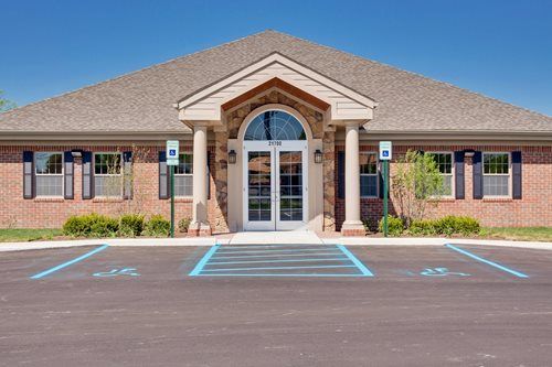 Front entrance of a brick office building with parking spaces and handicap access markings