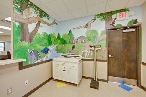 Mural-painted room with sink, exit door, and nature scene on the walls