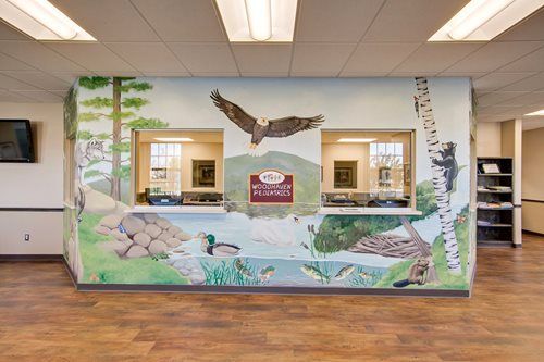 Indoor lobby with a mural of an eagle, trees, rocks, and a pond on a central wall panel