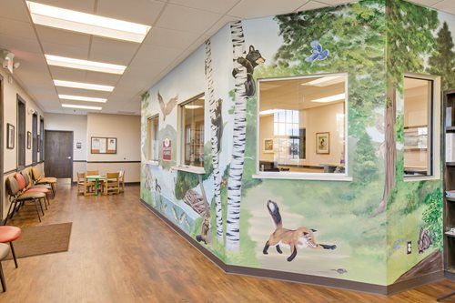 Bright hallway with a colorful mural of trees and animals in a medical or school setting