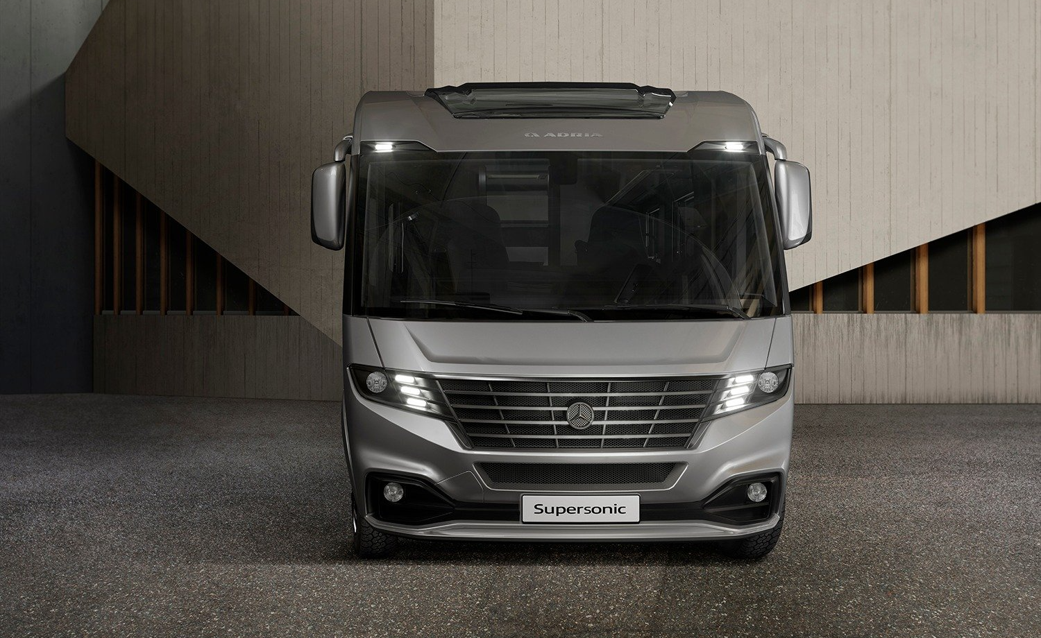 Gray recreational vehicle parked in front of a modern building.