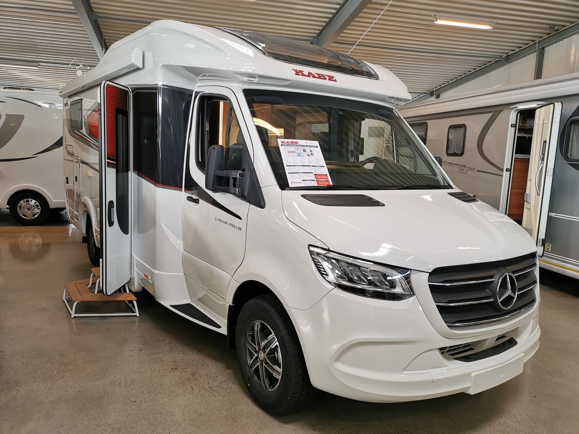 White camper van with open door, parked indoors.