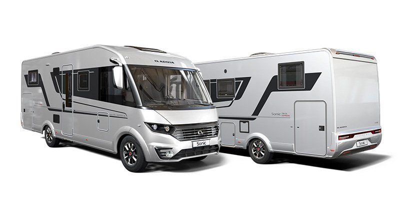 Two silver recreational vehicles parked outdoors.