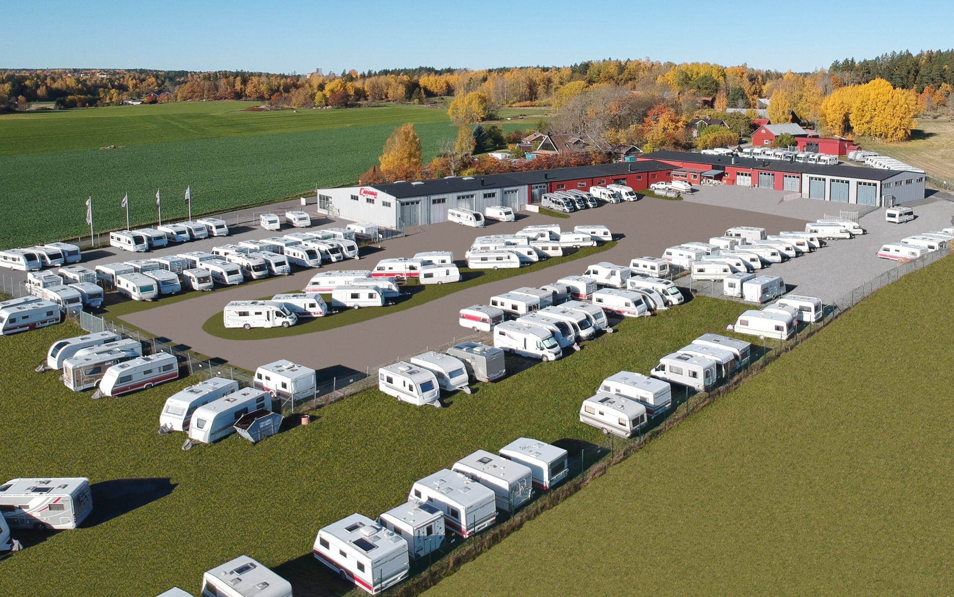 Aerial view of a caravan sales lot with rows of white campers, set in a rural landscape with buildings.