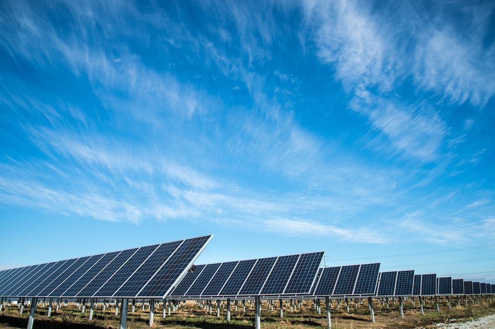 Solar panels generating energy in a field against a blue sky