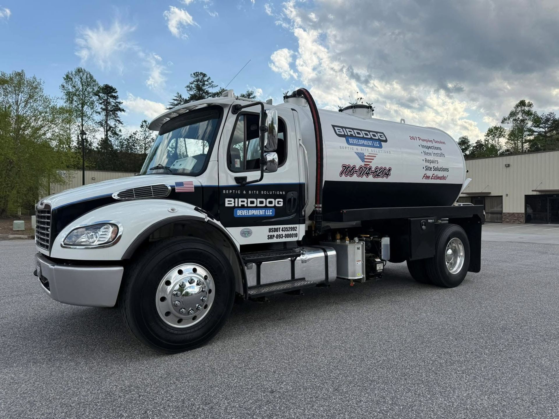 White and black dump truck parked on gravel lot under cloudy sky