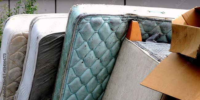 Old mattresses and cardboard boxes piled up outside.