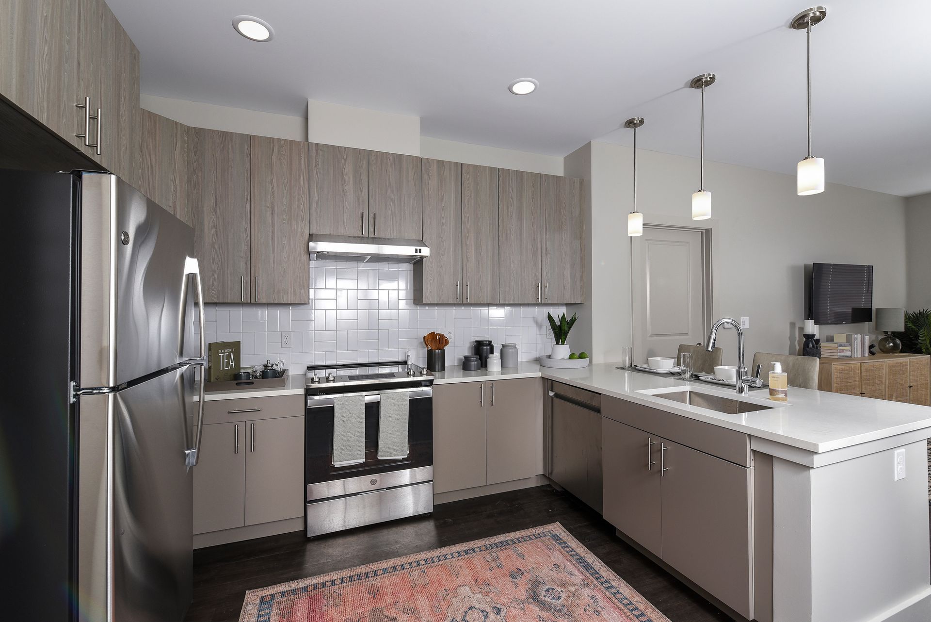 Modern kitchen with light wood cabinets, stainless steel appliances, and a white countertop island.