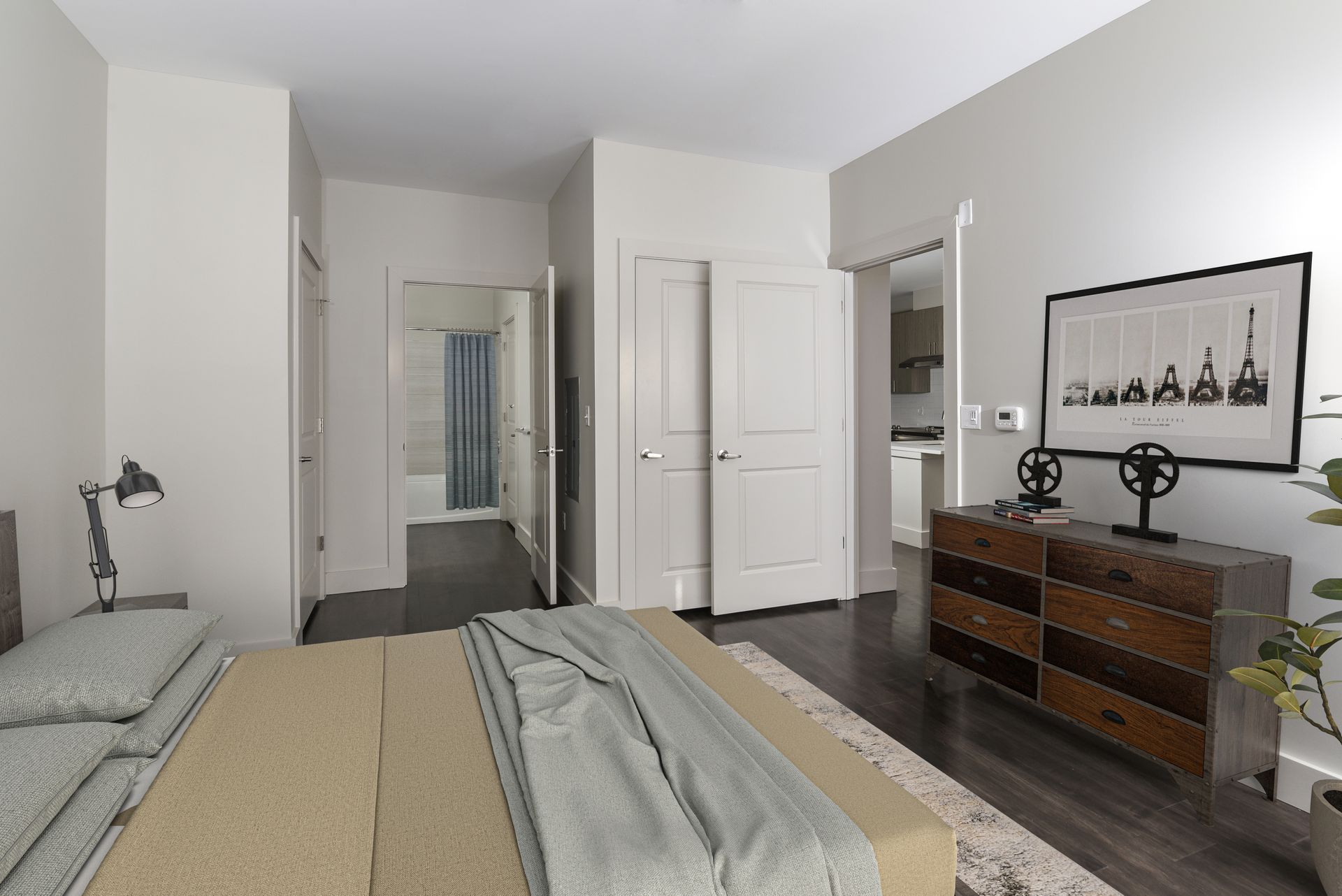 Bedroom with bed, dresser, doors leading to bathroom and kitchen.