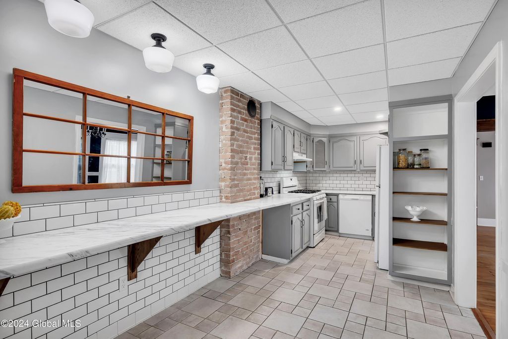 A kitchen with white cabinets and a brick wall