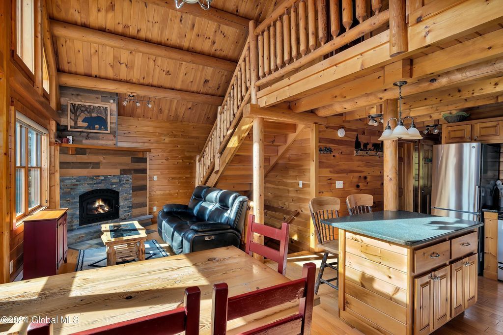 The inside of a log cabin with a table and chairs and a fireplace.