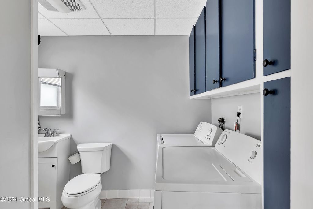 A bathroom with a toilet , sink and washer and dryer