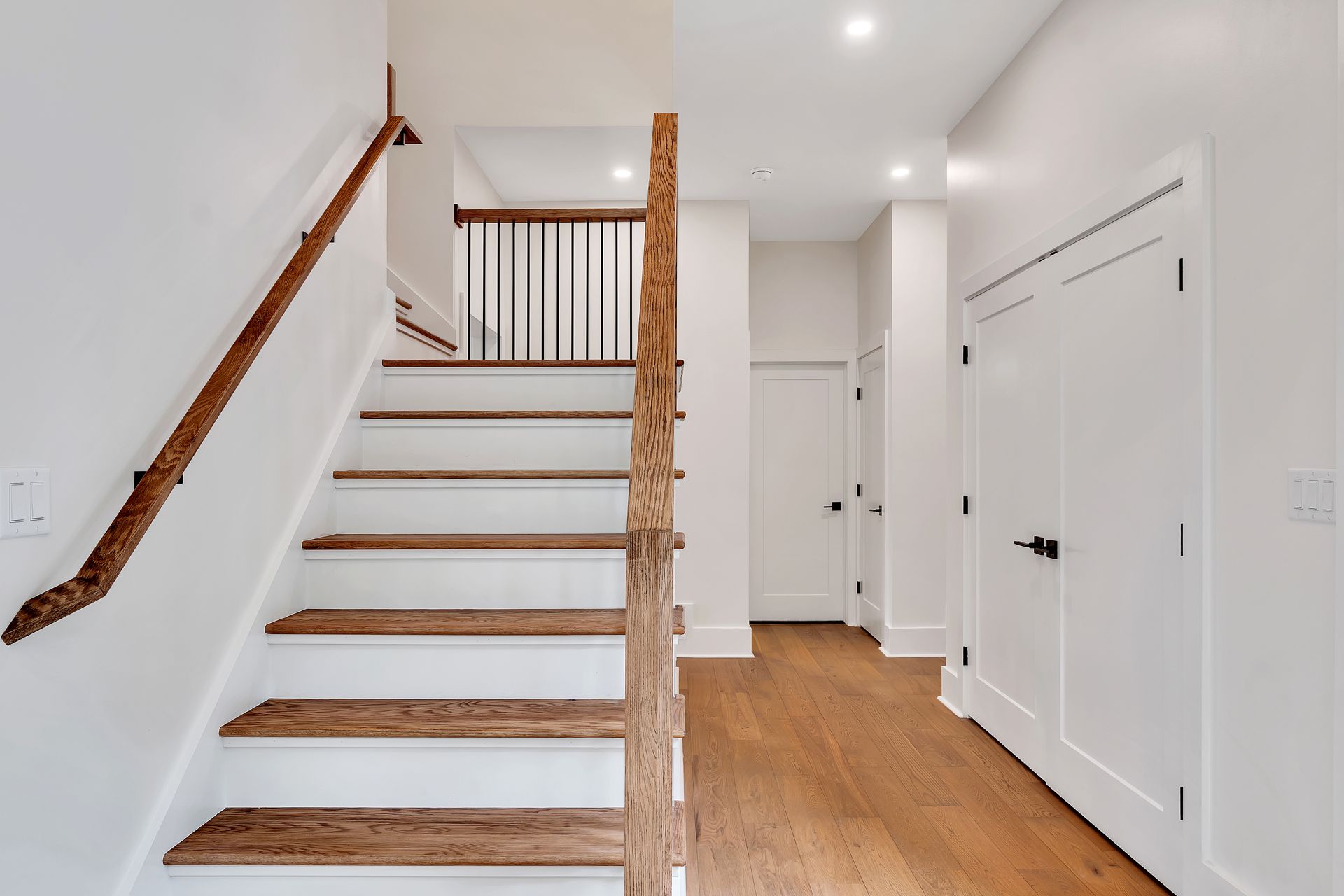 A staircase with wooden steps and a wooden railing in a hallway.