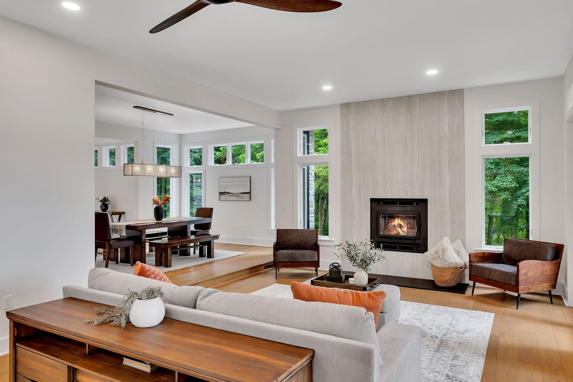 A living room with a couch , chairs , a fireplace and a ceiling fan.