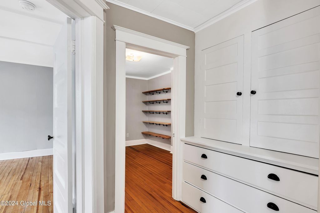 A hallway in a house with a dresser and shelves
