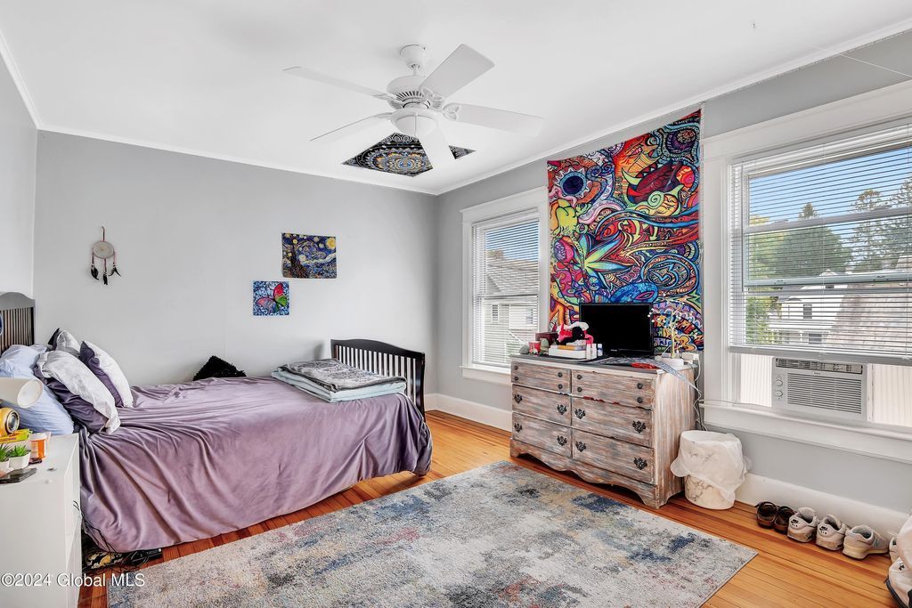 A bedroom with a bed , dresser , and ceiling fan.