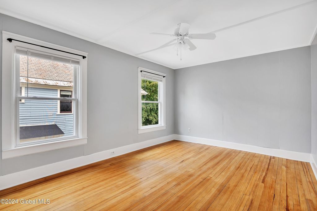 An empty room with hardwood floors and a ceiling fan.