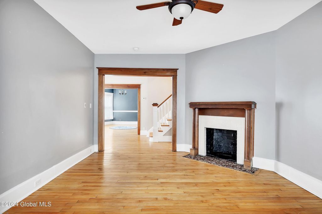 An empty living room with a fireplace and a ceiling fan.