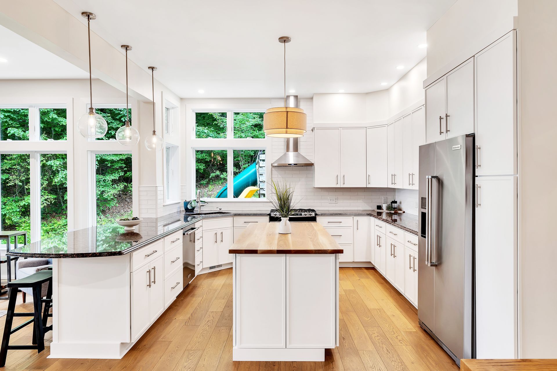 A kitchen with white cabinets , stainless steel appliances , and a large island.