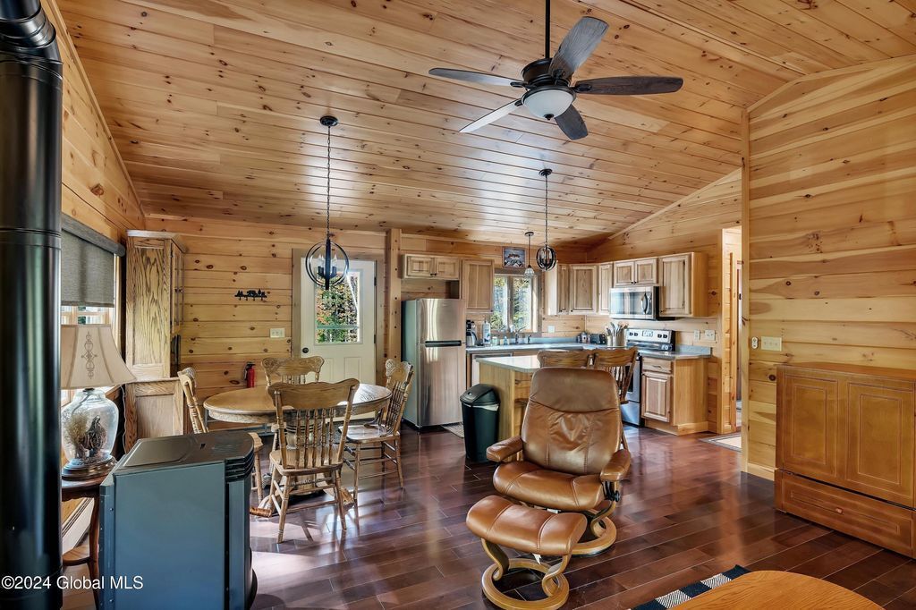 A living room in a log cabin with a ceiling fan