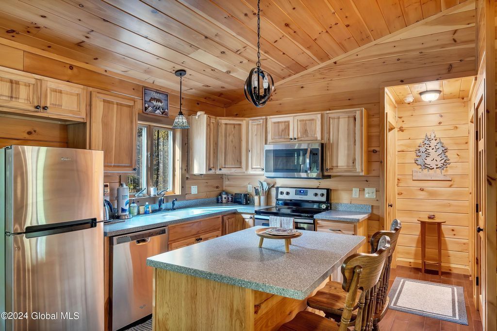 A kitchen in a log cabin with stainless steel appliances and wooden cabinets.