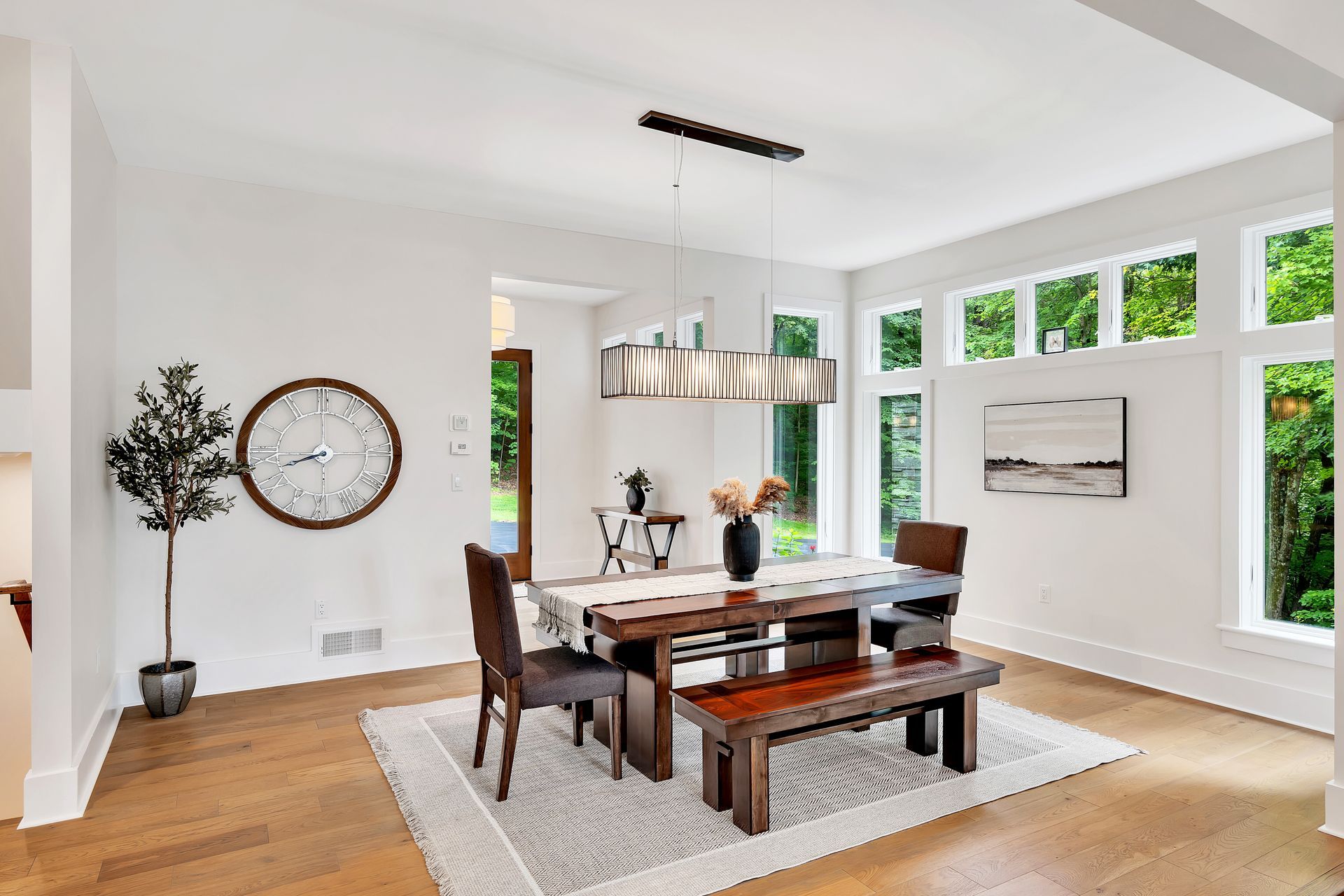 A dining room with a table and chairs and a clock on the wall.