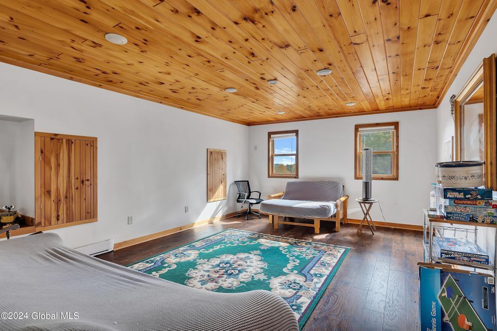 A living room with a couch and a rug and a wooden ceiling.