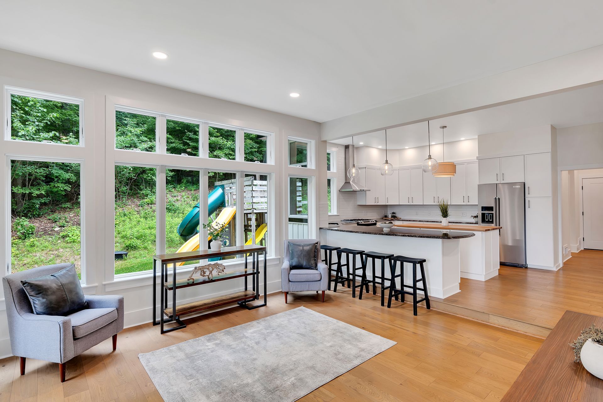 A living room filled with furniture and a kitchen with a playground in the background.