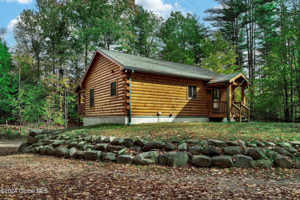 A small wooden house is surrounded by trees and rocks.
