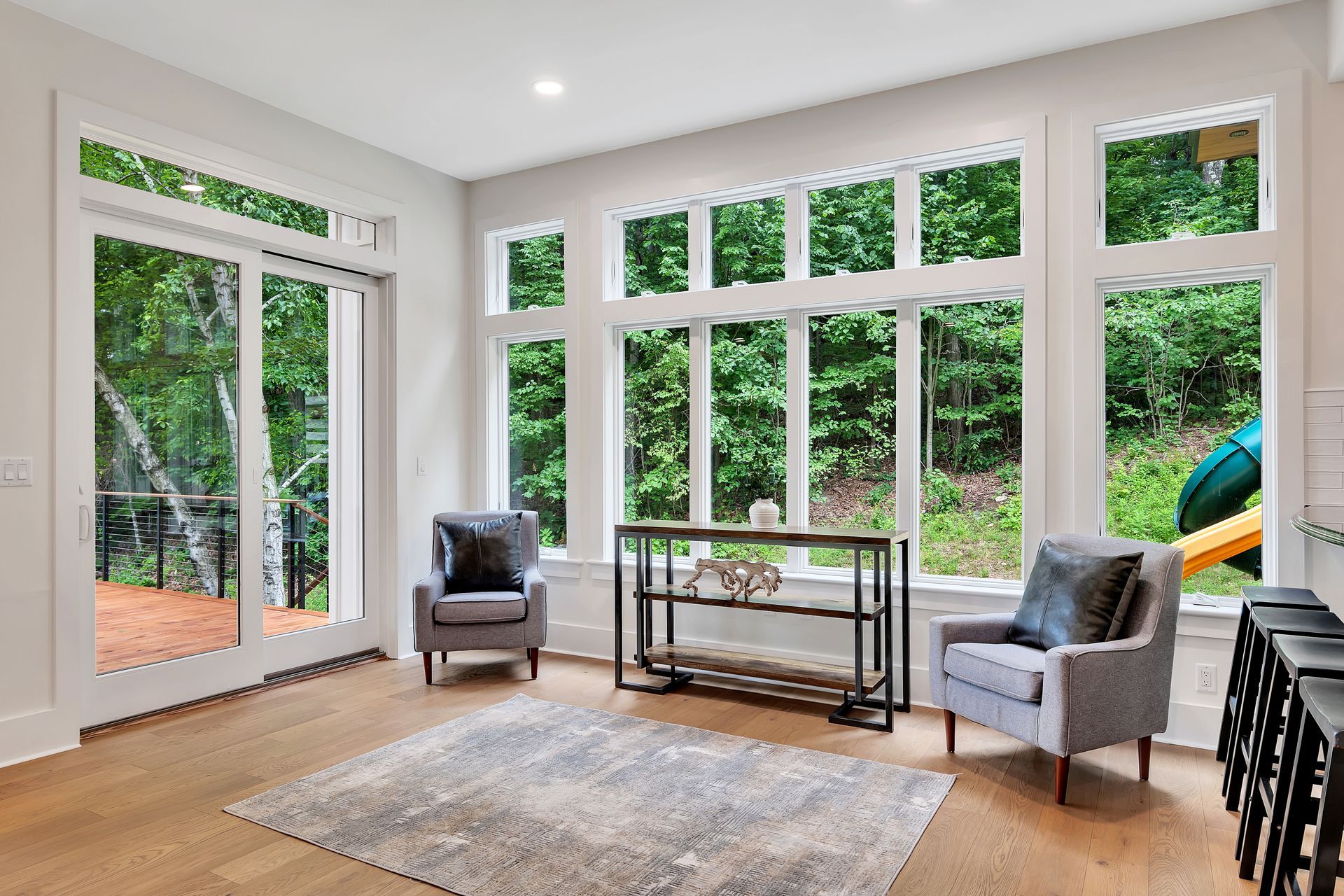 A living room with a lot of windows and chairs.