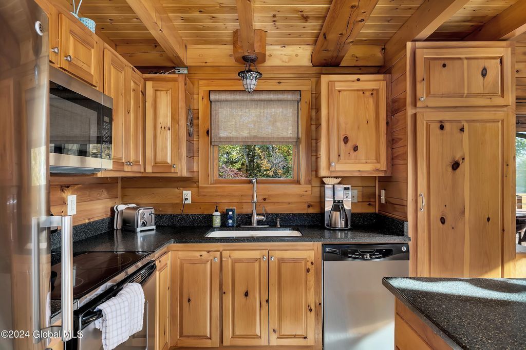 A kitchen in a log cabin with wooden cabinets and stainless steel appliances.