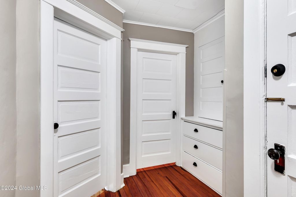 A hallway with white doors and wooden floors in a house.