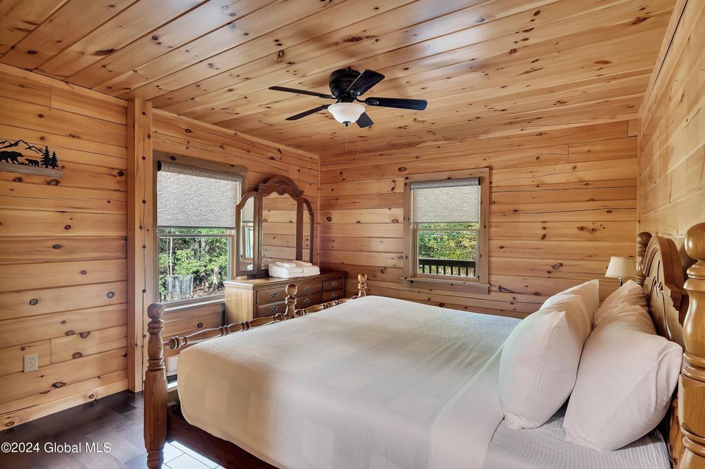 A bedroom in a log cabin with a king size bed and a ceiling fan.