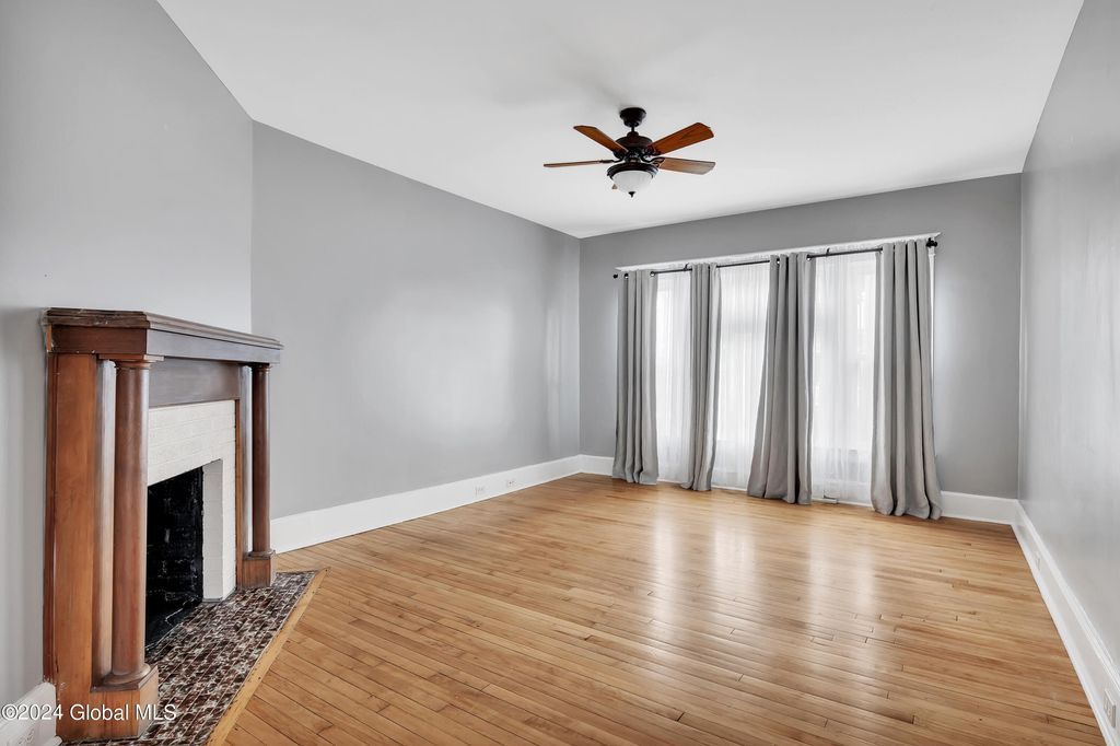 An empty living room with a fireplace and a ceiling fan.