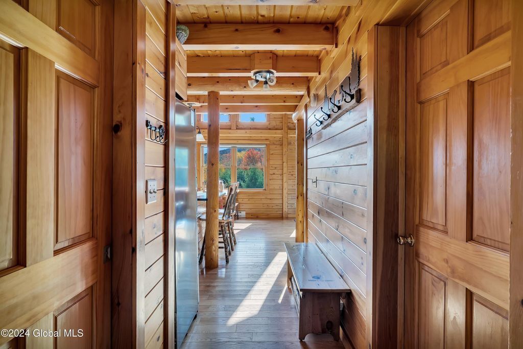 A hallway in a log cabin with wooden doors and a bench.