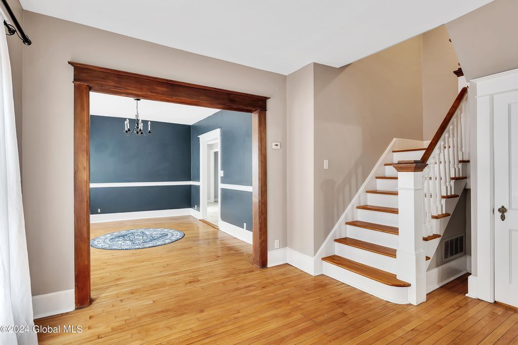 An empty living room with hardwood floors and stairs leading up to the second floor.