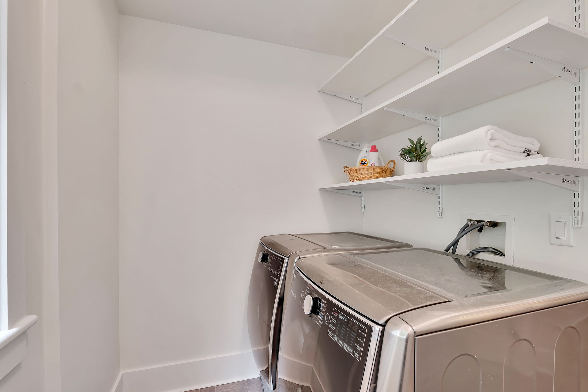 A laundry room with a washer and dryer and shelves.
