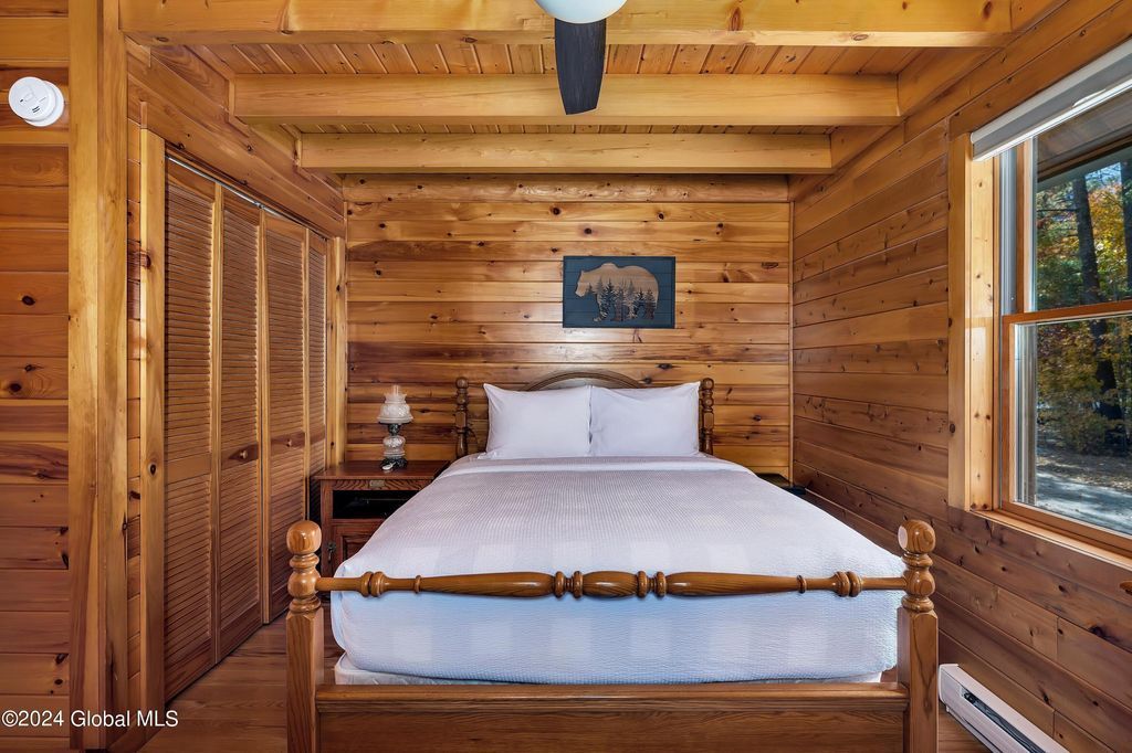 A bedroom in a log cabin with a bed and a ceiling fan.