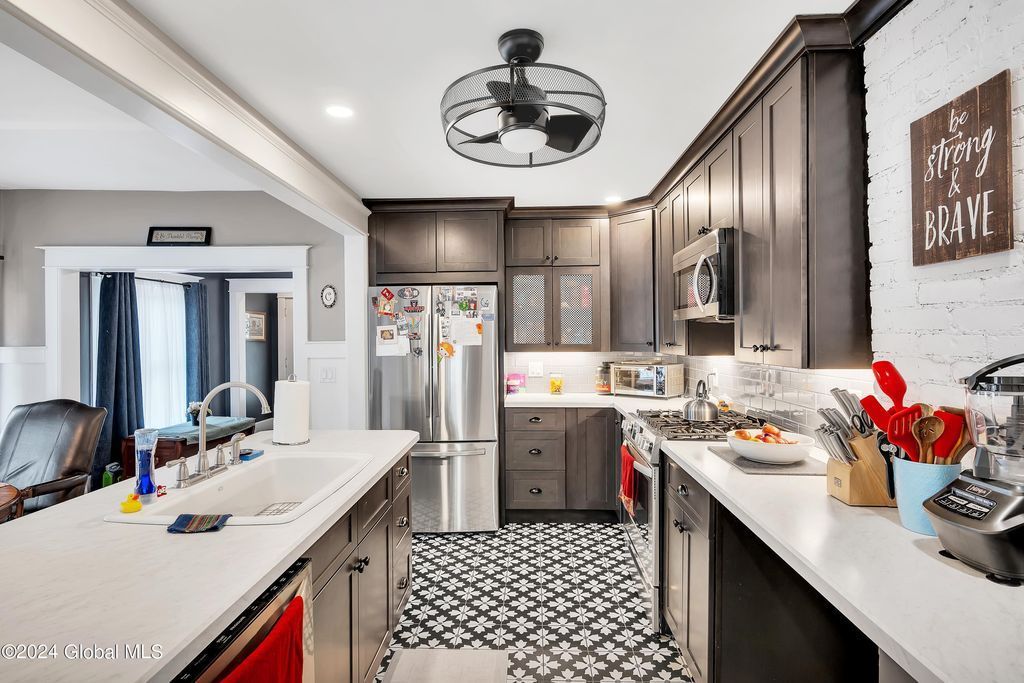 A kitchen with stainless steel appliances and a ceiling fan.