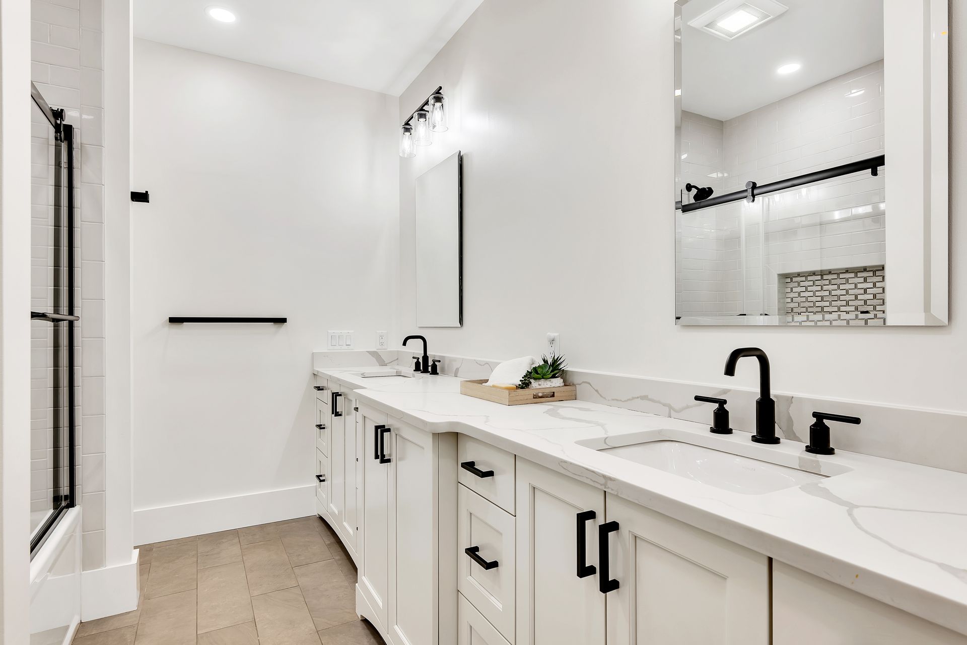 A bathroom with two sinks , a mirror and a walk in shower.