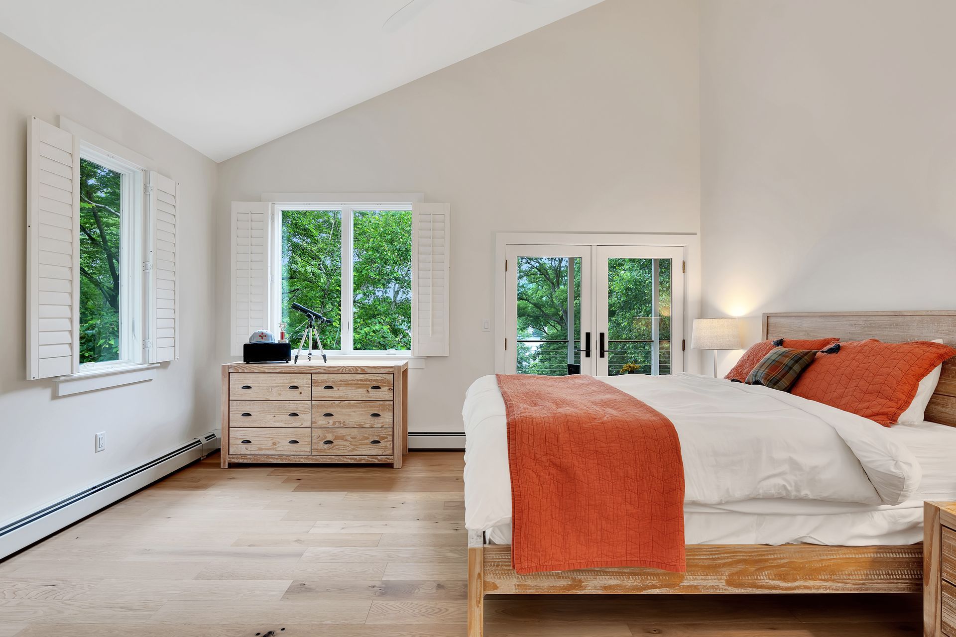 A bedroom with a king size bed , dresser , and two windows.