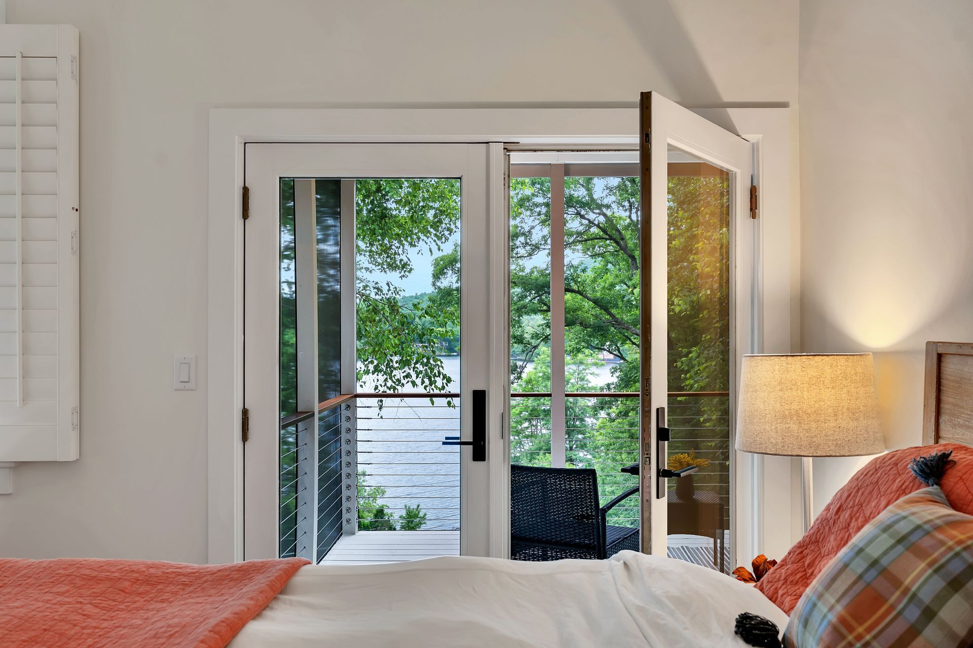 A bedroom with a bed , lamp , and sliding glass doors leading to a balcony.