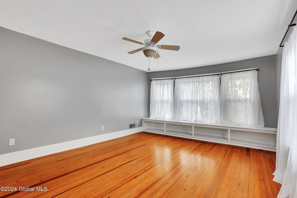 An empty living room with hardwood floors and a ceiling fan.
