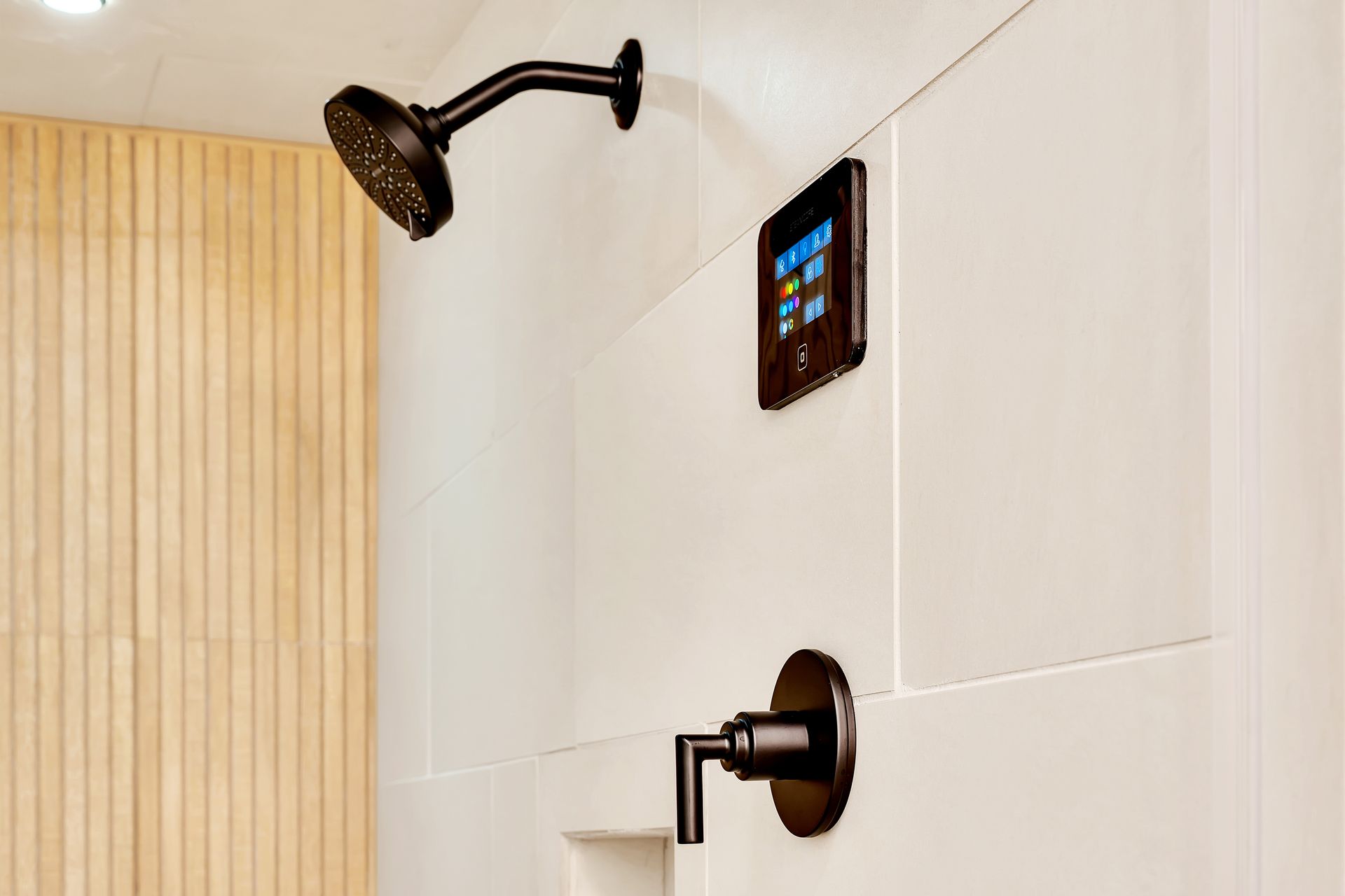 A bathroom with a shower head and a thermostat on the wall.