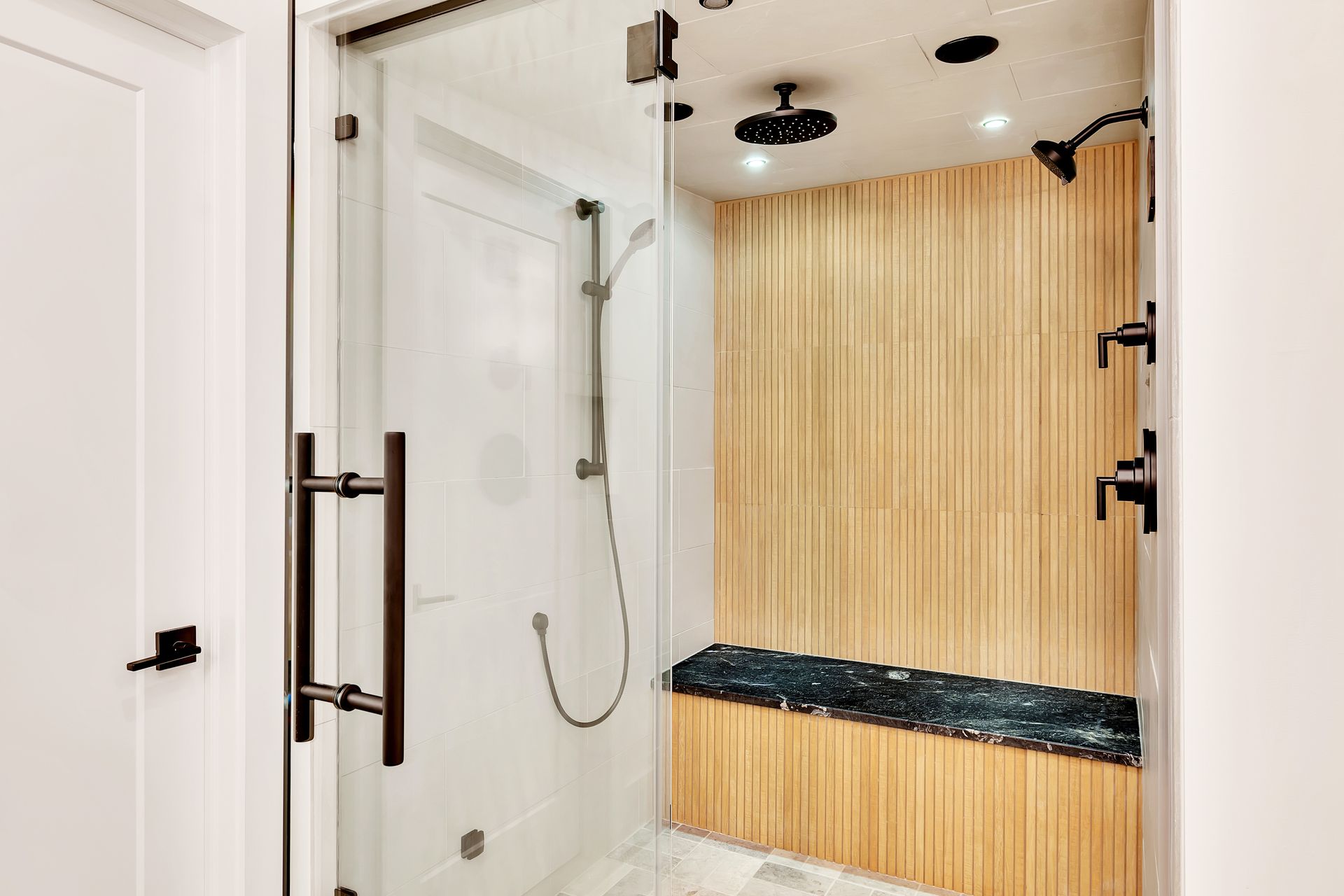 A bathroom with a walk in shower and a bench.
