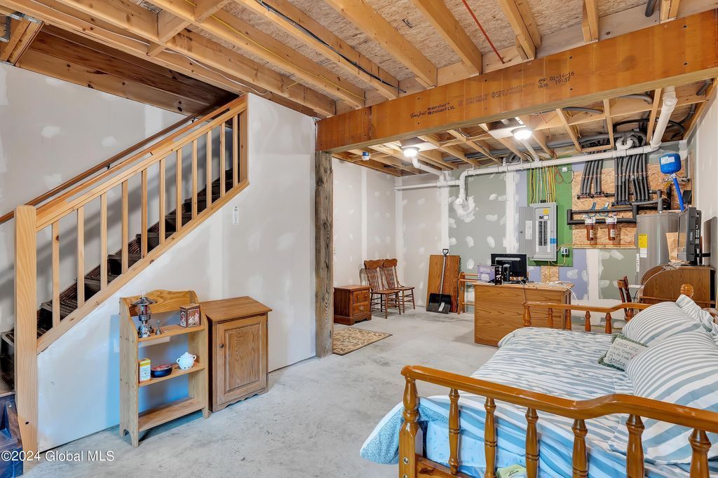 A bedroom in a basement with a bed and stairs.