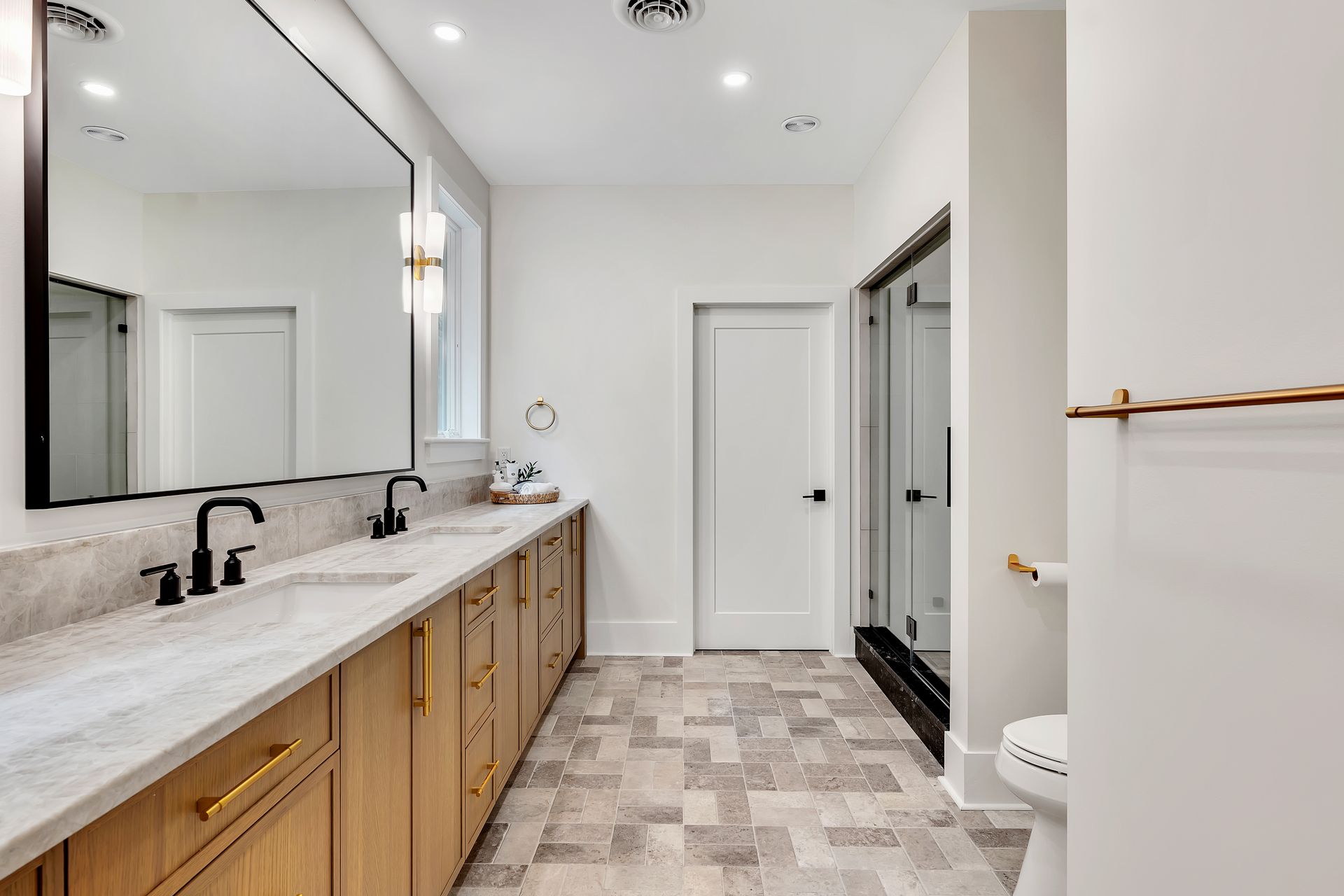 A bathroom with two sinks , a toilet , and a large mirror.