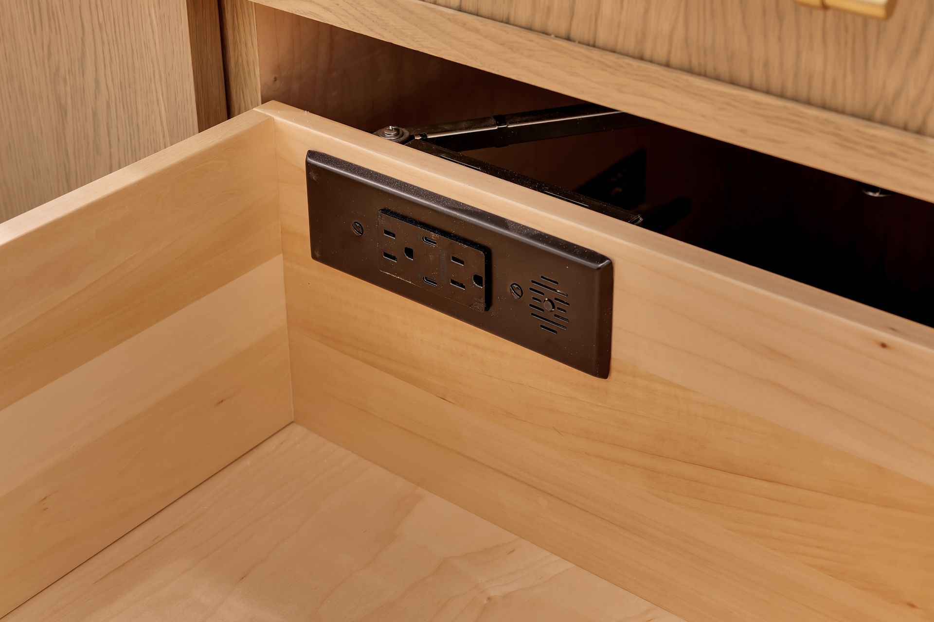 A wooden drawer with a black electrical outlet in it