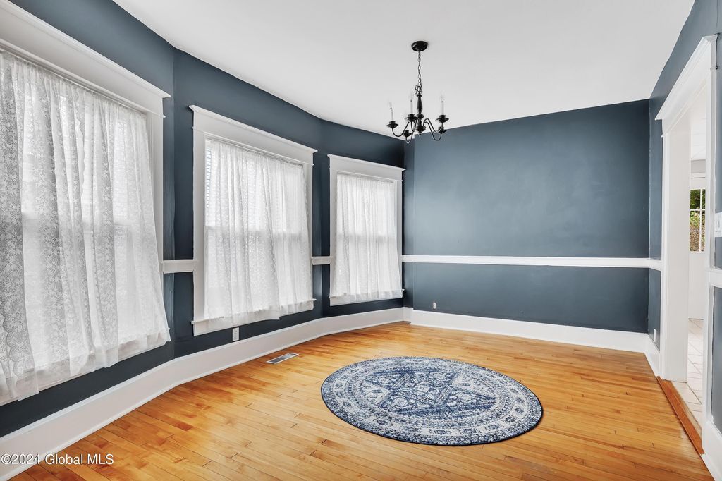 An empty room with a rug and a chandelier