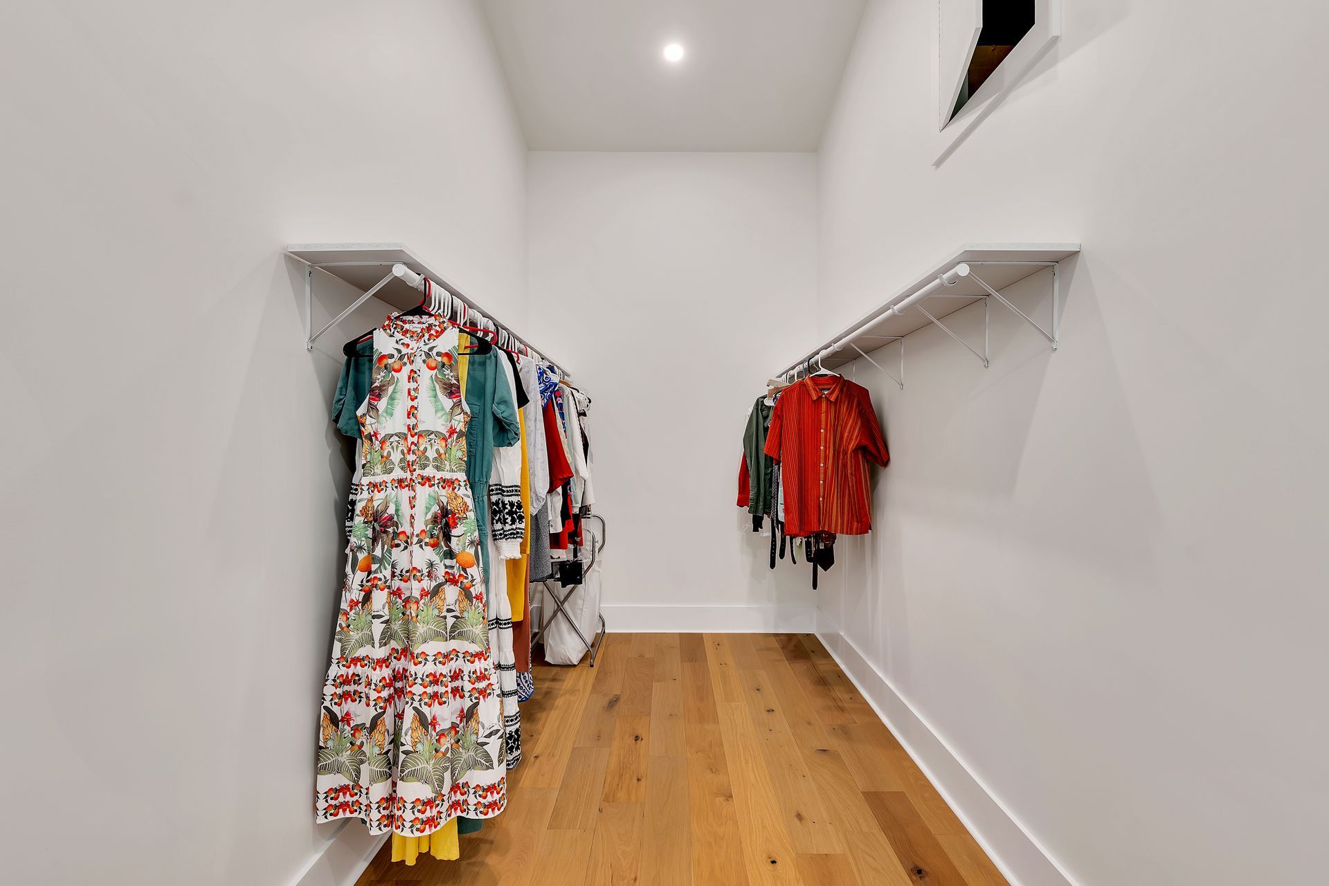 A walk in closet with a lot of clothes hanging on racks.